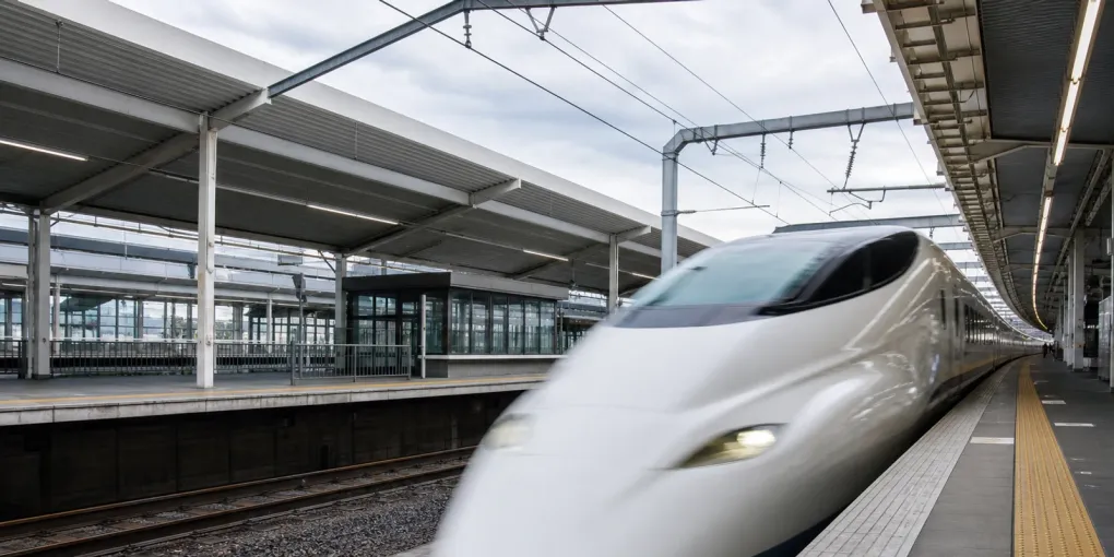 A shinkansen pulling into a Japanese station platform, seen from the platform edge
